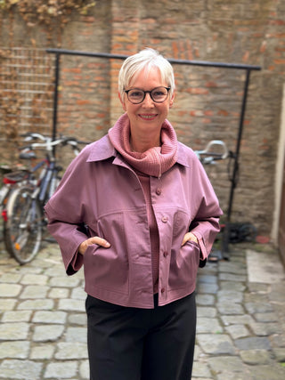 Frau trägt die kurze Jacke JACKIE von lackenau in Altrosa, Vorderansicht mit Händen in den aufgesetzten Taschen