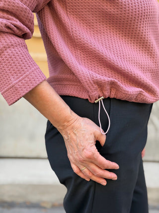 Nahaufnahme des Saums mit Kordel und silberfarbenem Kordelstopper, Pullover HERBSTA rosa